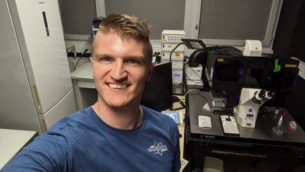 Kevin Scrudders in the lab in Marseille, beside an inverted microscope