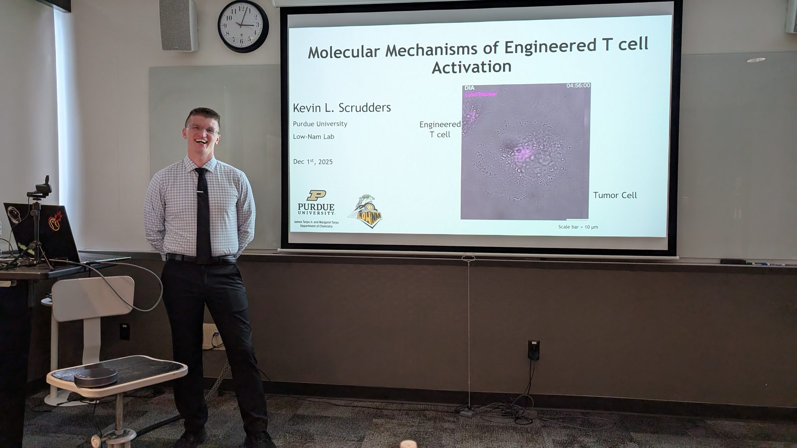 Kevin Scrudders beside the opening title slide of his thesis defense